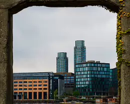Concrete Window Twin cylindrical glass towers framed by weathered concrete arch on Copenhagen waterfront.