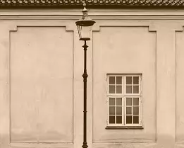 Quiet Street Central vintage streetlamp before plaster wall and window in Copenhagen.