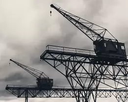 Industrial Giants Two lattice steel harbor cranes silhouetted against cloudy sky in Copenhagen.