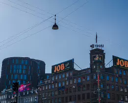Urban Junction JOB billboard and thermometer tower on Rådhuspladsen beneath crossing twires, Copenhagen.