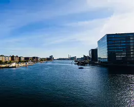 Waterfront Lines Kalvebod Brygge canal with modern glass offices and historic brick blocks lining water in Copenhagen.