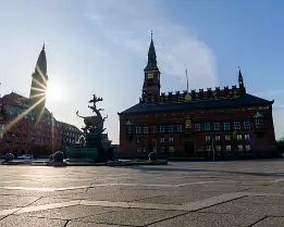 Sunburst Spire Dragon Fountain and Copenhagen City Hall stand prominently on Rådhuspladsen under a low sun.