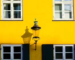 Historic Hue Lantern shadow on bright yellow Nyboder facade with white windows in Copenhagen.