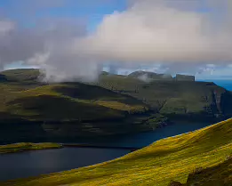 Rolling Hills Clouds drifting over green hills and fjords in the Faroe Islands.