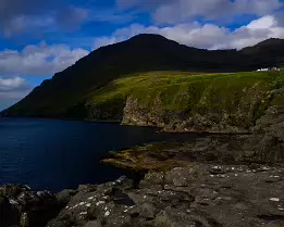 Cliffside Dwellings Cliffs and rocky shore with scattered houses overlooking the sea in the Faroe Islands.