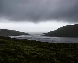 Heavy Skies Lake Sørvágsvatn leading toward the Atlantic Ocean where it drains into Bøsdalafossur Waterfall near Trælanípa in the Faroe Islands.