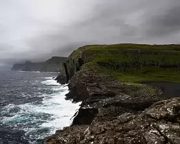 Crashing Surf Rocky cliffs with sharp outcrops against the Atlantic in the Faroe Islands.