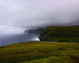 Grassy Heights Grassy slopes above the Trælanípa cliffs overlooking the Atlantic Ocean in the Faroe Islands.
