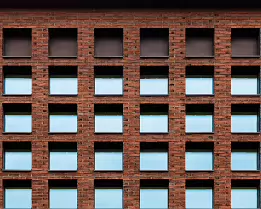 Uniform Pattern Grid of square windows in red-brick façade at Helsinki University’s Kaisa House library.