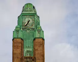 Copper Spire Clock tower of Helsinki Central Railway Station against a cloudy sky.