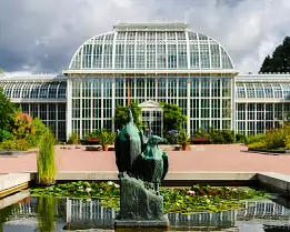 Botanical Refuge Palm House glass greenhouse with bird sculpture and lily pond in Kaisaniemi Botanic Garden, Helsinki.