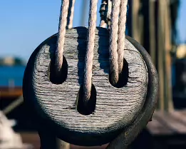 Rope Tension Close-up of a wooden pulley with ropes on a docked sailing ship in Helsinki.