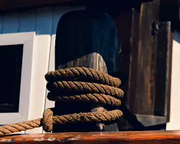 Nautical Detail Thick rope coiled around a wooden post on the deck of a boat in Helsinki harbor.