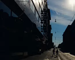 City Shadows Silhouetted pedestrians crossing a quiet city street with modern buildings in Helsinki.