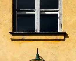 Vintage Light A weathered yellow wall with an old lamp and a wooden-framed window on Länsi-Mustasaari Island in the Suomenlinna district of Helsinki.