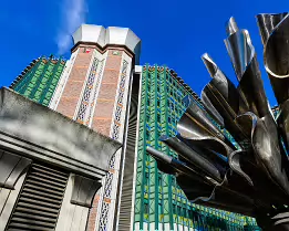 Futuristic Facade Oblique view of a modernist Vienna building with green panels and a stainless-steel flower-like sculpture against a clear blue sky.