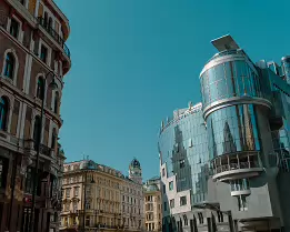 Mirror Contrast Glass-clad Haas Haus and neighbouring historic façades meet under a clear sky at a central Vienna intersection.