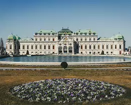 Baroque Grandeur Symmetrical façade of Vienna’s Upper Belvedere Palace reflected in its ornamental pool beyond spring flowerbeds.